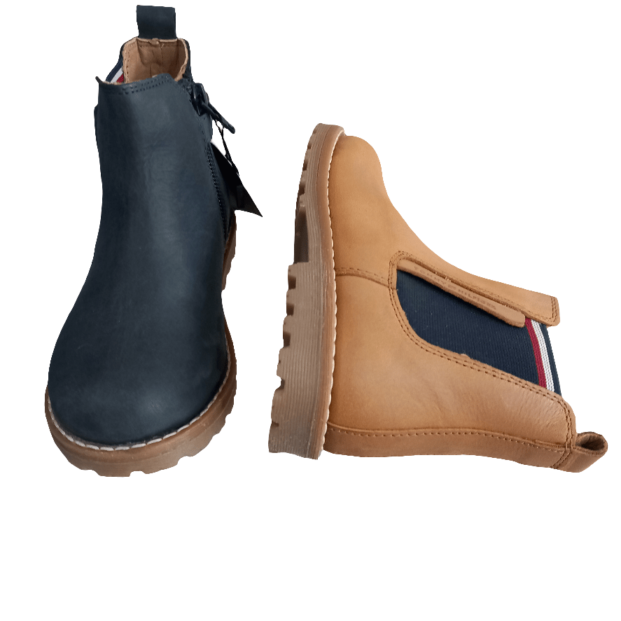 Stivaletti Chelsea bambino in pelle, uno nero e uno beige, con elastico laterale blu a righe.